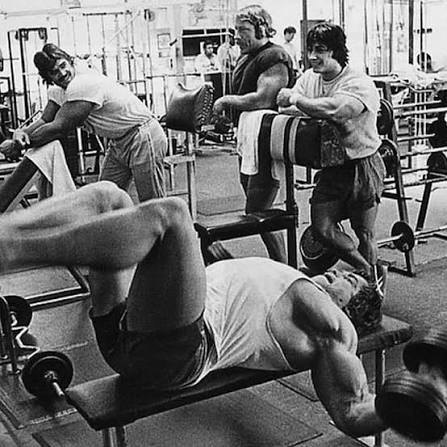 Black-and-white photo of bodybuilders training together in a 1970s Venice Beach gym